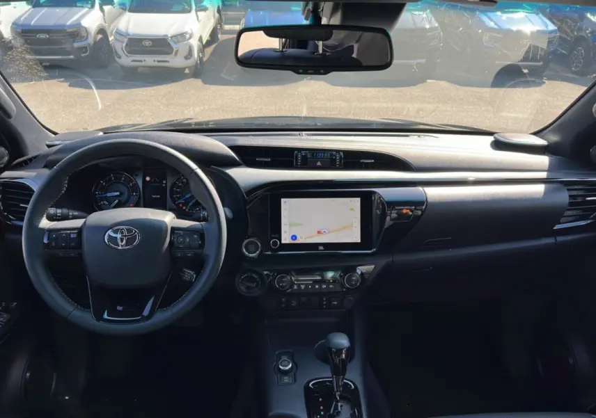 Vue intérieure du tableau de bord du Toyota Hilux 2025 gris atlas, avec écran tactile et volant multifonction.