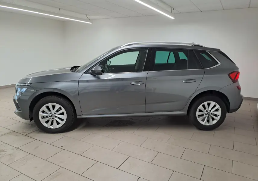 Vue de profil côté gauche d'un Skoda Kamiq gris graphite 2025 avec jantes alliage et caméra de recul intégrée.