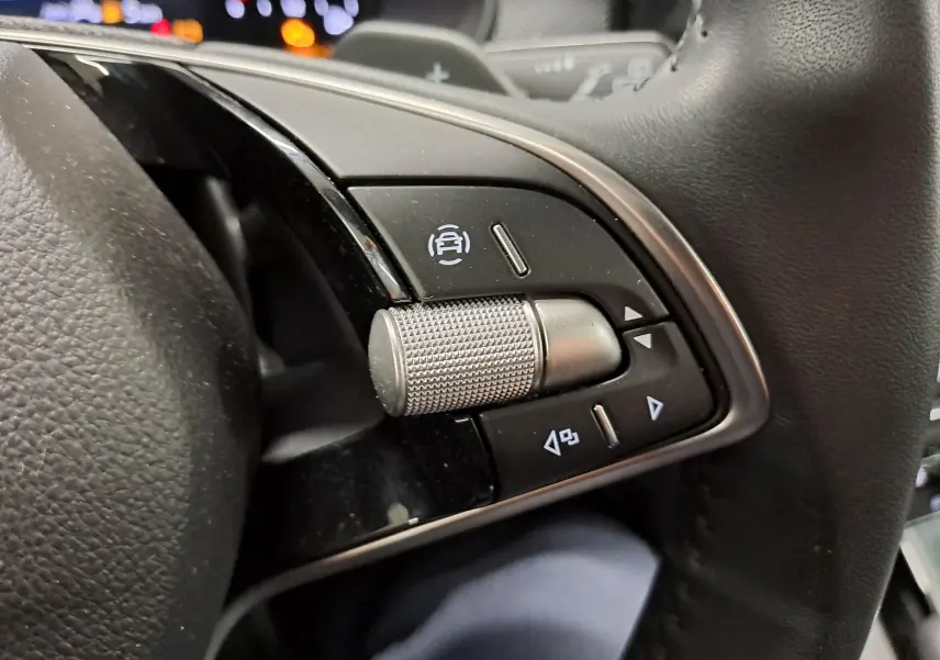 Gros plan sur les commandes au volant du Skoda Kamiq 2025, avec molette métallique et boutons noirs.