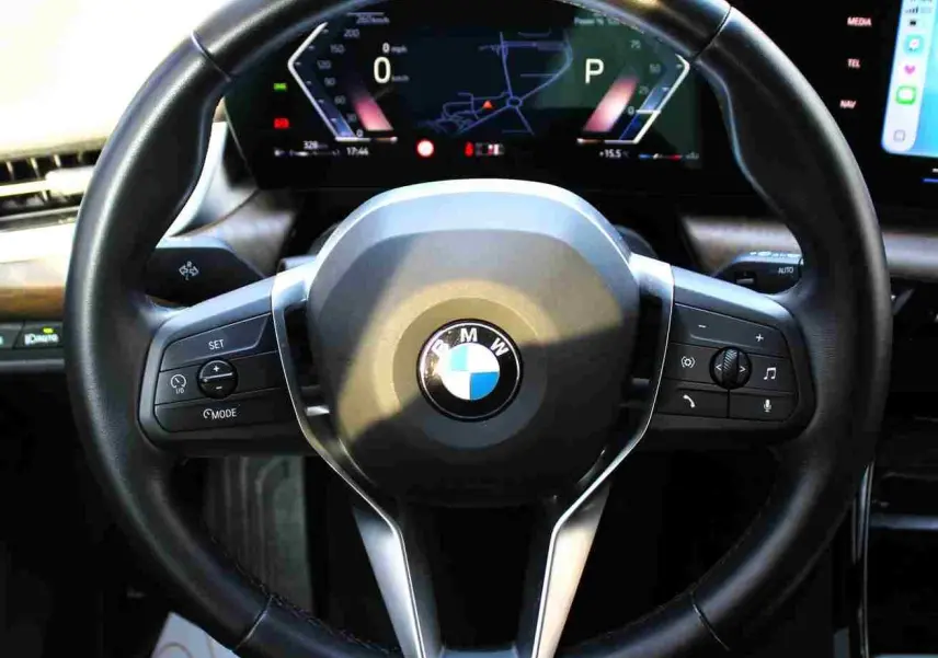 Gros plan sur le volant cuir noir et le tableau de bord numérique d'une BMW Série 2 Active Tourer gris Nardo.