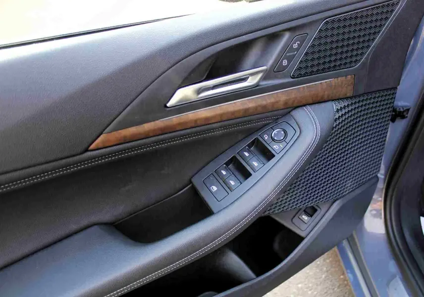 Gros plan sur la porte avant gauche de la BMW Série 2 Active Tourer gris Nardo, avec commandes électriques et insert bois.