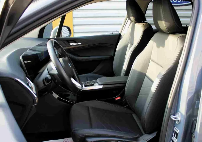 Vue intérieure côté conducteur de la BMW Série 2 Active Tourer gris Nardo, sièges cuir noir et tableau de bord moderne.