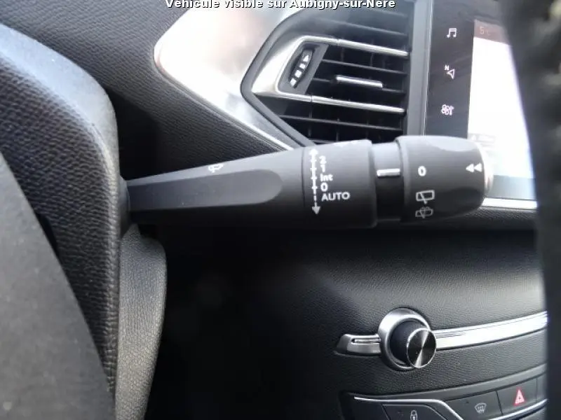 Gros plan sur la commande d'essuie-glace à gauche du volant dans l'habitacle noir du Peugeot 308 SW 2018.