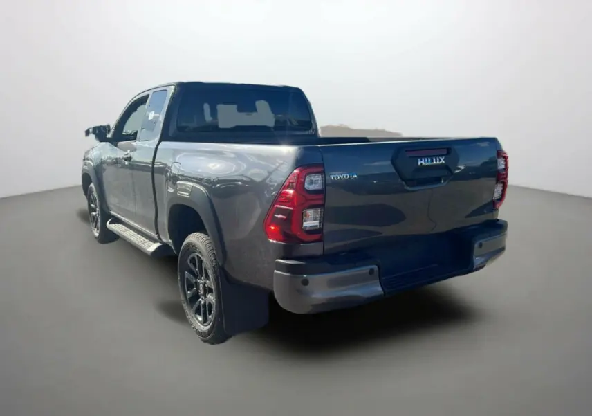 Toyota Hilux 4x4 gris atlas en vue 3/4 arrière droit, avec logo et feux arrière distinctifs visibles.