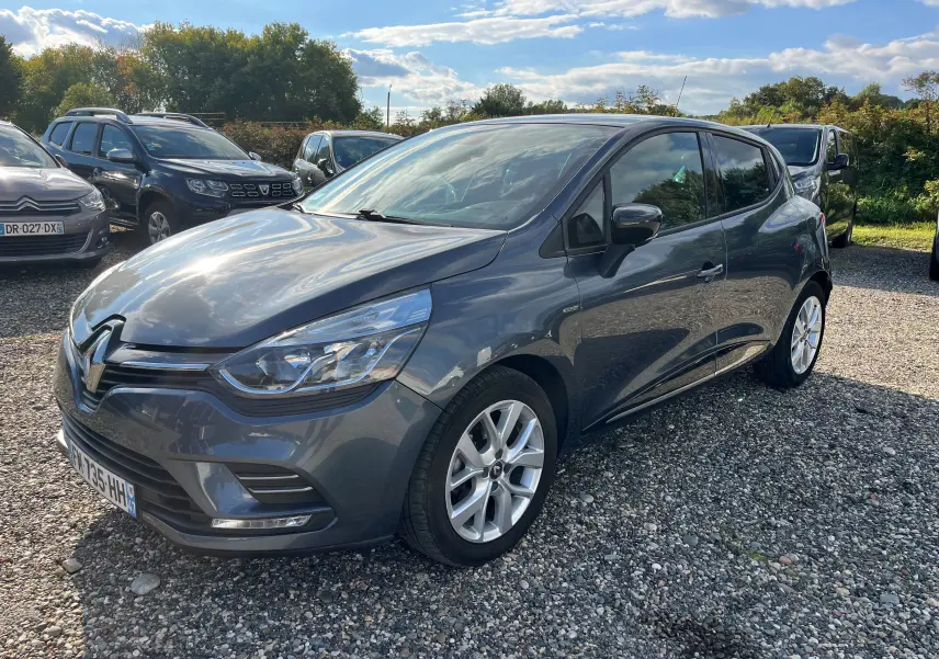 Vue avant d'une Renault Clio IV gris métallisé 2019 avec plaques françaises, garée sur un sol gravillonné.