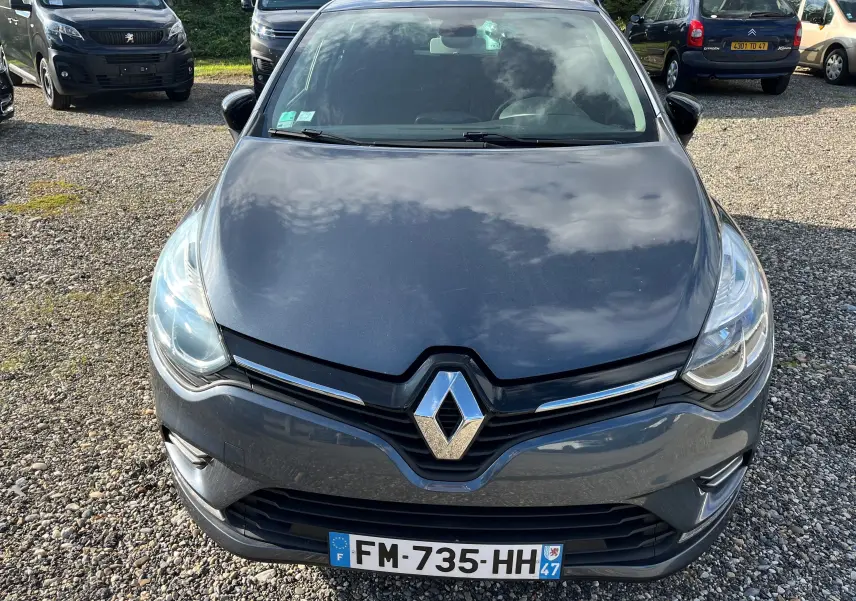 Renault Clio IV diesel gris métallisé vue 3/4 avant droit sur parking extérieur par temps ensoleillé.