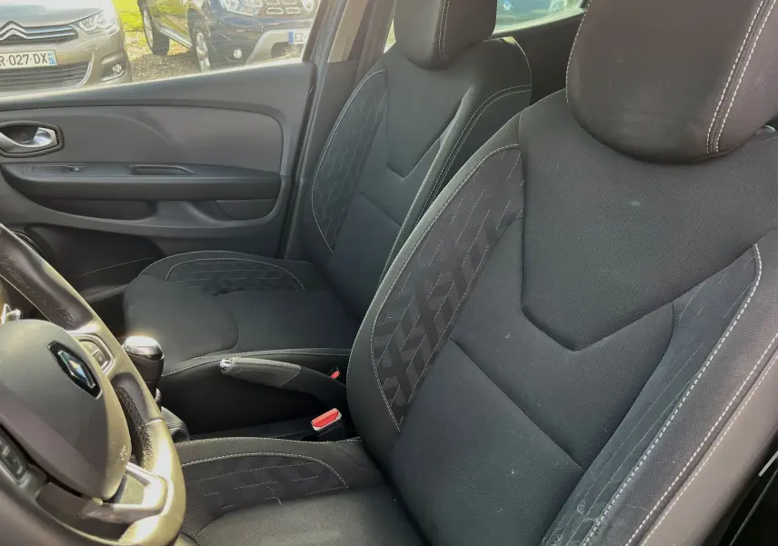 Vue intérieure sur les sièges avant en tissu noir et volant de la Renault Clio IV diesel 2019, côté gauche visible.