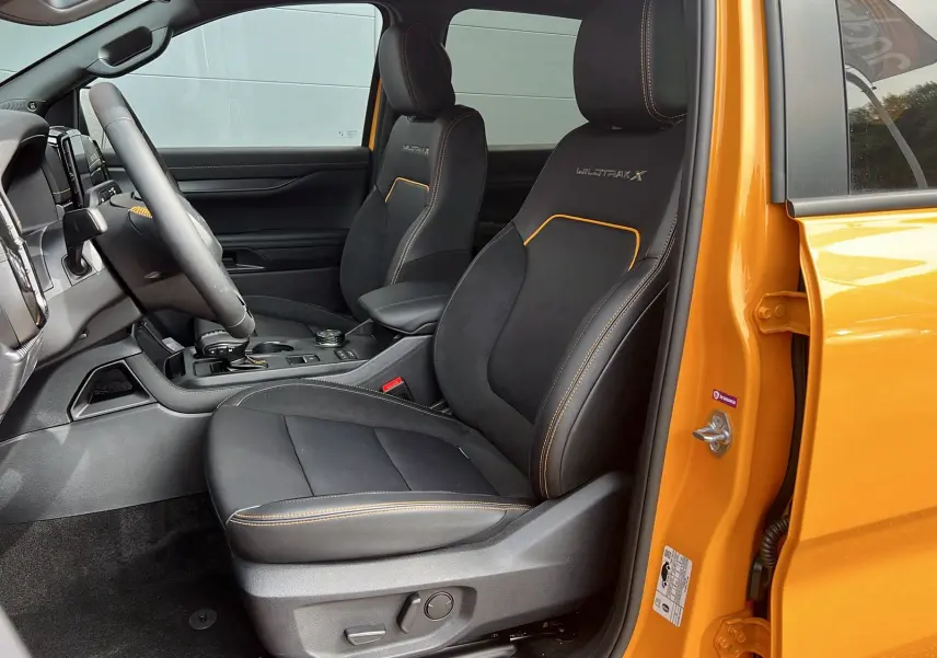 Vue intérieure côté conducteur du Ford Ranger 2025 Cyber orange, sièges Wildtrak X avec surpiqûres orange visibles.