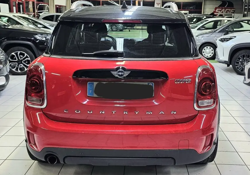 Vue arrière d'une MINI Cooper Countryman rouge avec toit noir, dans un showroom lumineux.