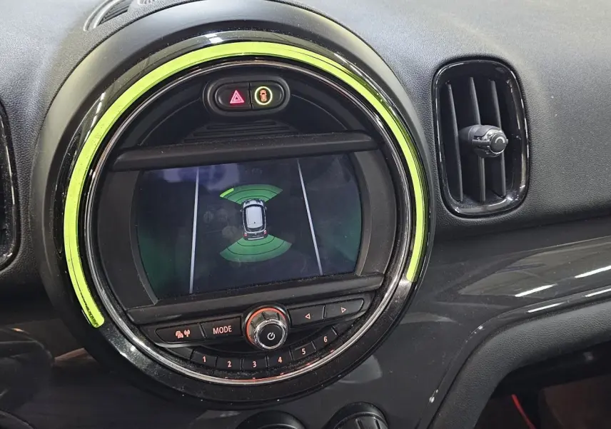 Vue rapprochée du tableau de bord du MINI Cooper Countryman 2018, avec écran central rond et éclairage vert autour.
