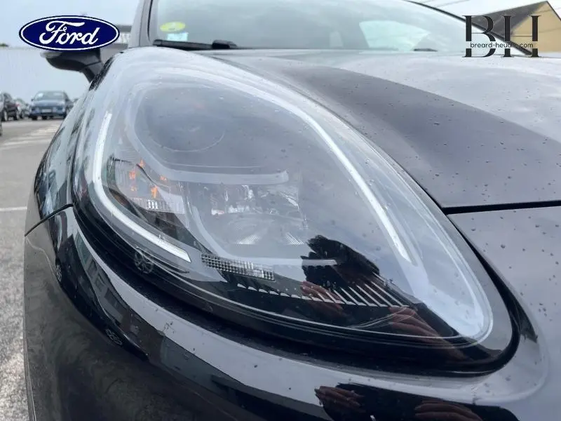 Gros plan sur le phare avant gauche du Ford Puma noir Agate Métallisée avec détails LED et carrosserie brillante.