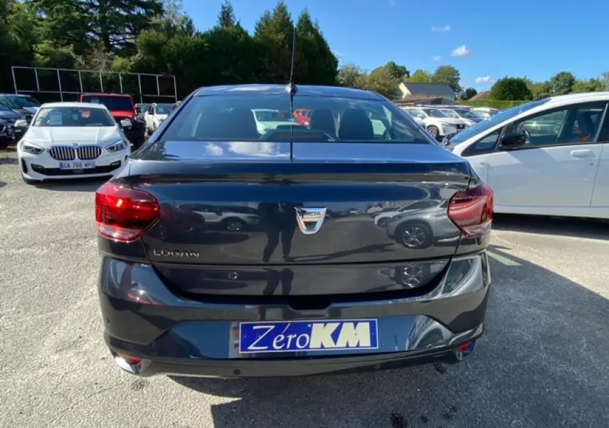 Vue arrière d'une Dacia Logan gris foncé 2022 avec feux rouges et plaque d'immatriculation Zéro KM visible.