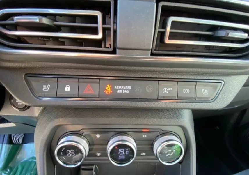 Vue rapprochée du tableau de bord de la Dacia Logan gris 2022, avec commandes climatisation automatique et voyants allumés.