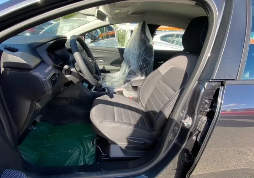 Intérieur côté conducteur de la Dacia Logan gris 2022, montrant le siège avant et le tableau de bord moderne.