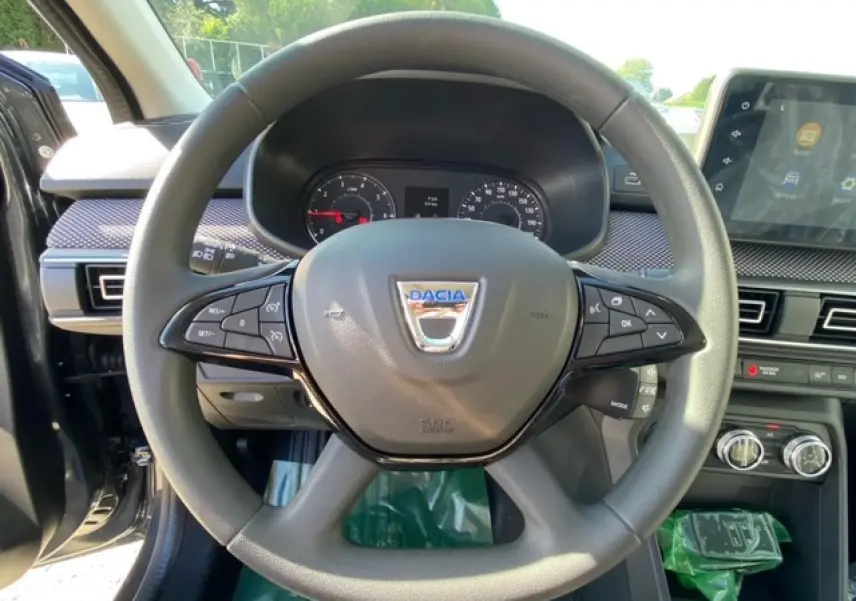 Vue rapprochée du volant gris de la Dacia Logan 2022 avec commandes intégrées et tableau de bord visible.