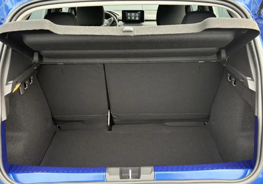 Coffre ouvert d'une Dacia Sandero Stepway bleu Iron, vue arrière montrant l'espace de chargement et l'intérieur noir.