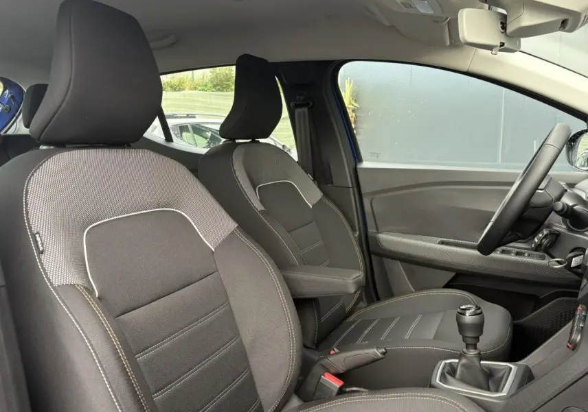 Vue intérieure côté droit de la Dacia Sandero Stepway 2025 Bleu Iron, sièges tissu avec accoudoir et volant Soft Feel.