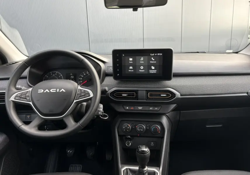 Vue intérieure frontale du tableau de bord et volant noir de la Dacia Sandero Stepway 2025 avec écran tactile central.