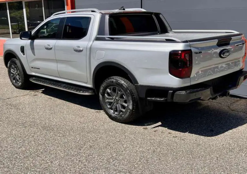 Ford Ranger 3.0 V6 240 Wildtrak Plus gris iconic vu en 3/4 arrière droit avec benne et jantes foncées.