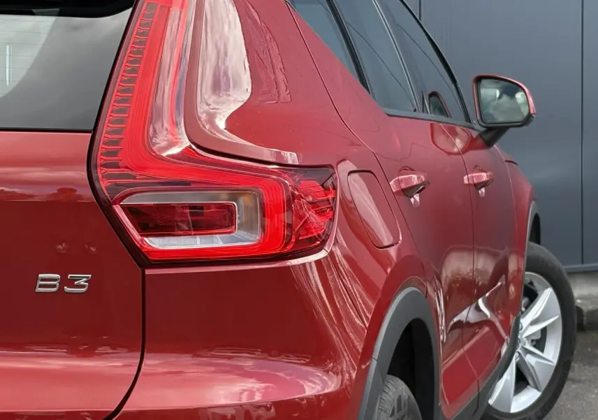 Vue 3/4 arrière droit du Volvo XC40 B3 MHEV rouge Fusion, mettant en valeur le feu arrière et la jante alliage 18 pouces.
