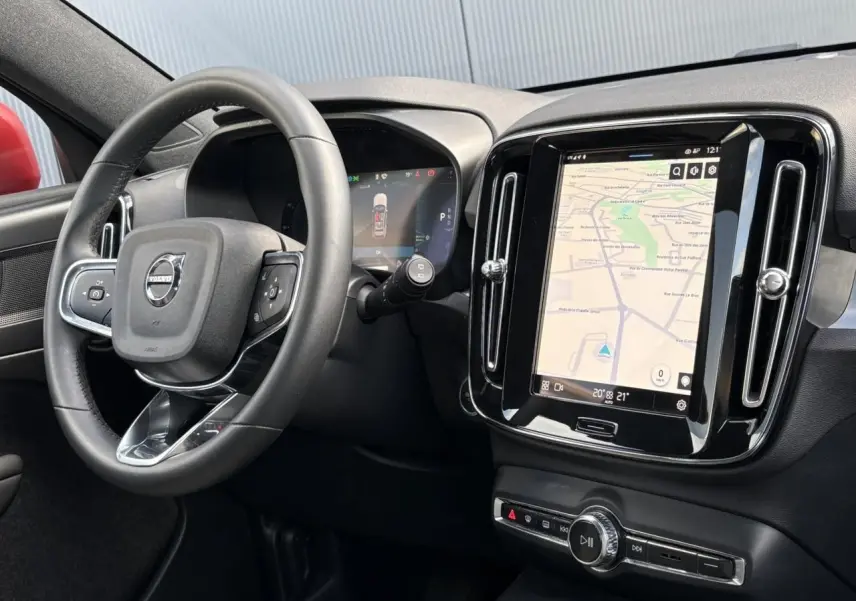 Intérieur du Volvo XC40 2024 vu côté conducteur, avec tableau de bord noir et écran tactile central affichant la navigation.