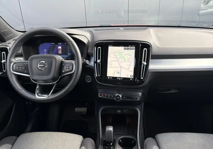Intérieur du Volvo XC40 2024, vue frontale du tableau de bord avec écran tactile et volant multifonction.