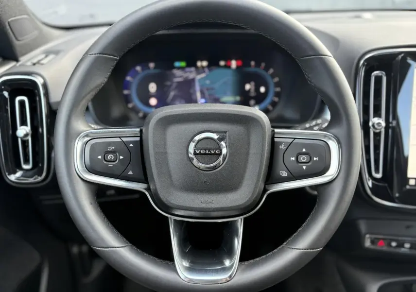 Volant cuir noir Volvo XC40 2024 vu de face avec commandes intégrées et tableau de bord digital flou.