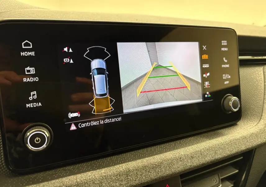 Écran multimédia affichant la caméra de recul et l'alerte de distance du Skoda Kamiq gris argent, vue intérieure du tableau de bord.