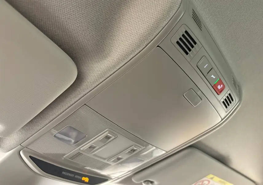 Vue intérieure du plafonnier gris clair avec commandes d'éclairage et indicateur airbag passager actif.