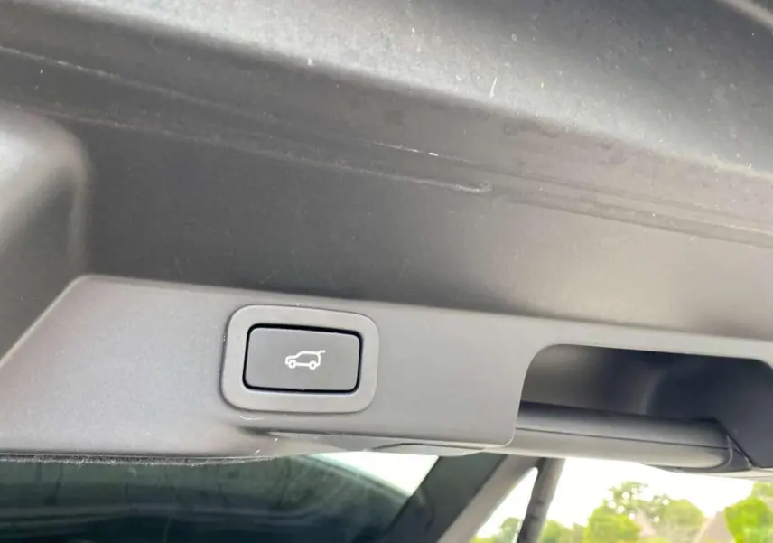 Bouton de commande du hayon électrique sur le bord intérieur du coffre d'un Range Rover Sport noir.
