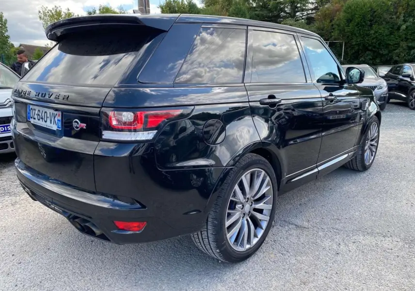 Range Rover Sport noir vu en 3/4 arrière droit, avec jantes 22 pouces et vitres arrière teintées.