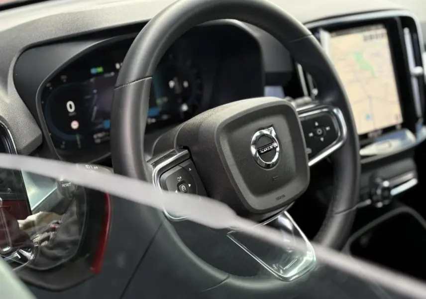 Gros plan sur le volant noir et le tableau de bord digital du Volvo XC40 B3 MHEV 2024 avec écran tactile GPS.