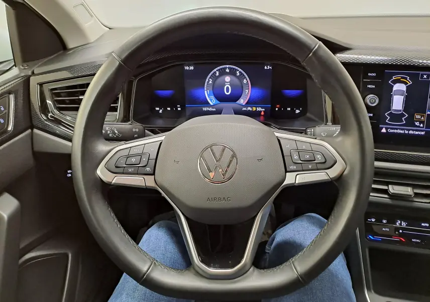 Vue intérieure centrée sur le volant noir du Volkswagen Taigo 2024 avec tableau de bord numérique et écran tactile.