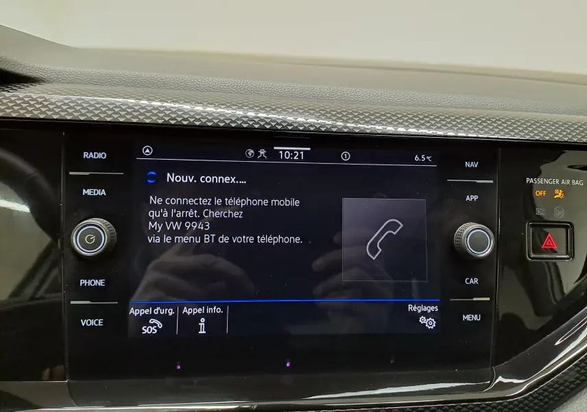 Écran tactile central du tableau de bord du Volkswagen Taigo blanc, affichant la connexion Bluetooth et commandes autour.