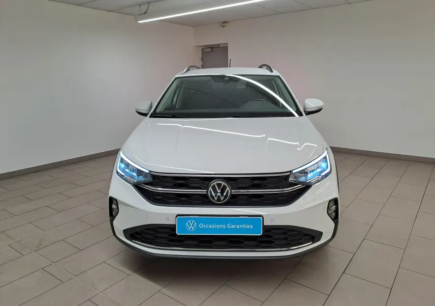 Volkswagen Taigo blanc pur vu de face, avec projecteurs LED allumés et calandre noire distinctive.