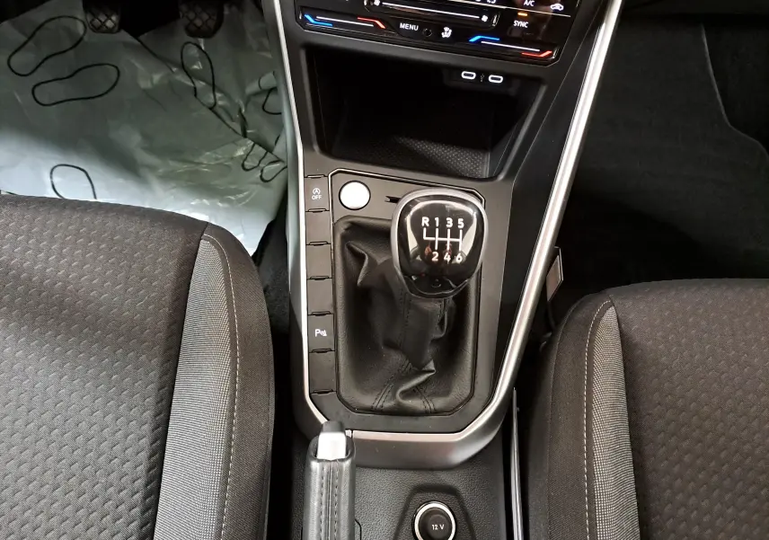 Vue plongeante sur la console centrale du Volkswagen Taigo 2024, avec levier de vitesse manuel et sièges tissu noirs.