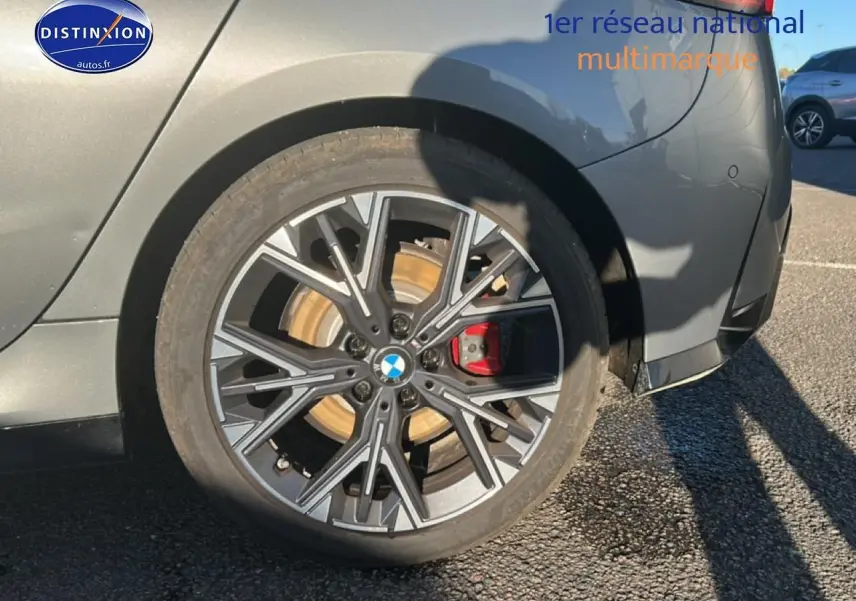Gros plan sur la roue arrière droite d'une BMW Série 1 gris Skyscraper avec jante 18 pouces bicolore en Y.