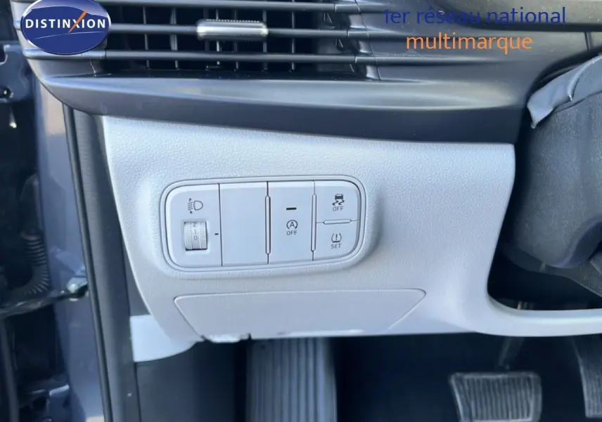 Gros plan sur les commandes de réglage d’éclairage et d’assistance côté gauche d’un Hyundai i20 gris Aurora Metal 2025.