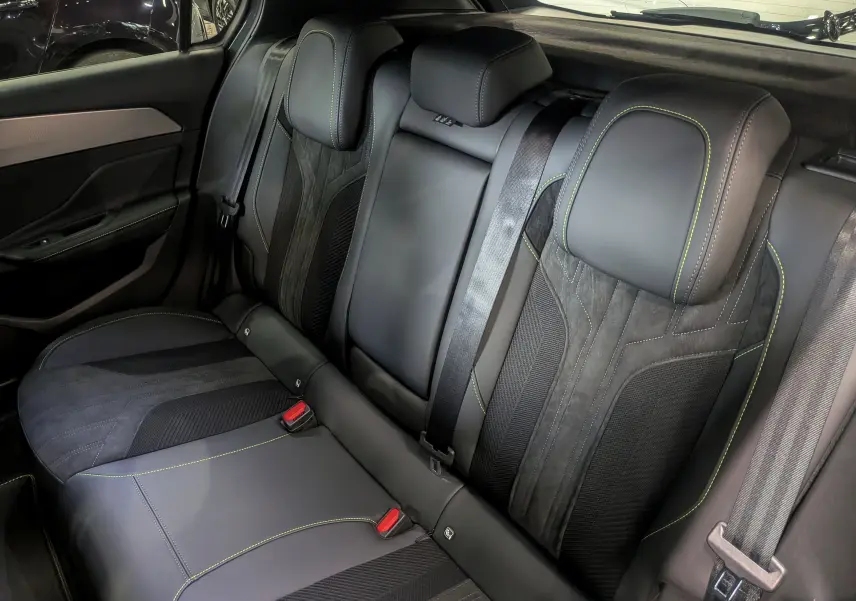 Vue intérieure des sièges arrière en cuir noir et alcantara avec surpiqûres vertes d'une Peugeot 308 GT Exclusive 2026.