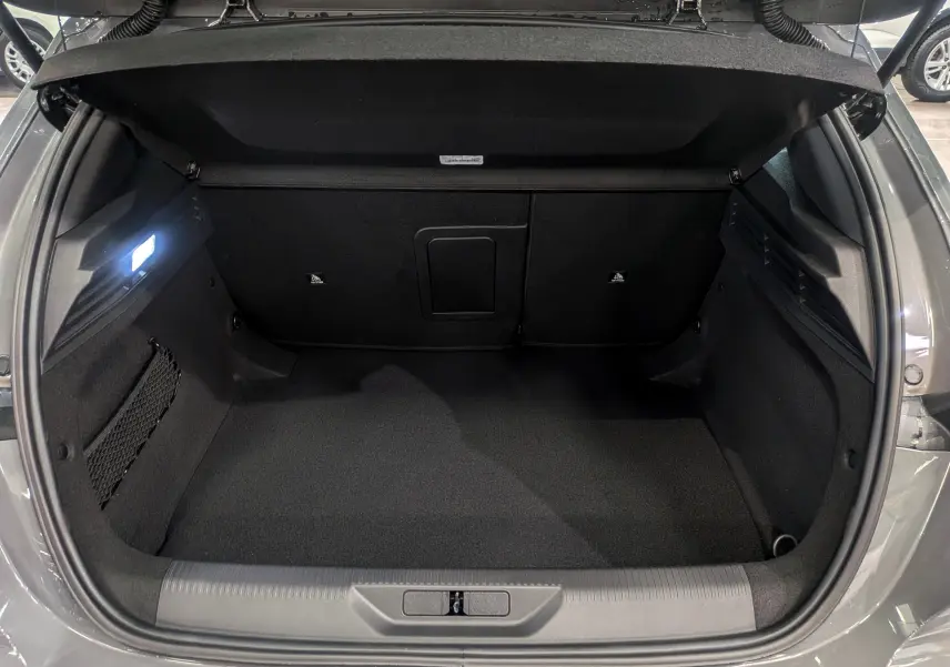 Coffre ouvert de la Peugeot 308 GT Exclusive gris Sélénium, montrant un espace de chargement propre et bien éclairé.