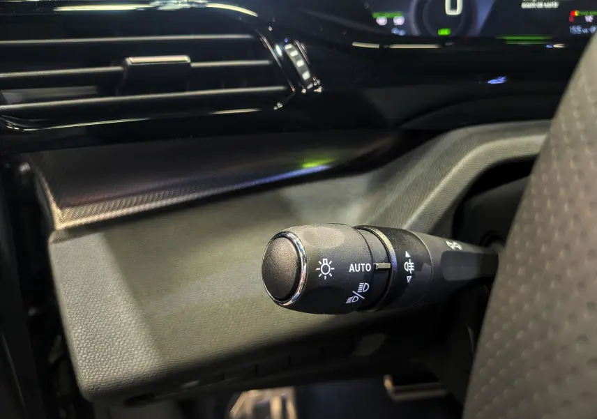 Gros plan sur la commande des feux côté gauche dans l’habitacle gris et noir de la Peugeot 308 GT Exclusive 2026.