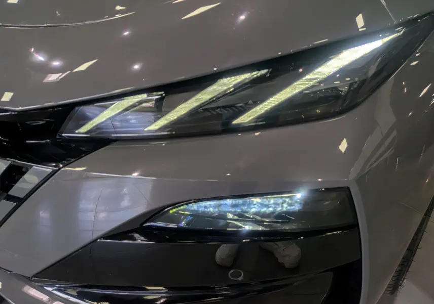 Gros plan sur le phare avant droit allumé d'une Peugeot 308 GT Exclusive gris Sélénium, mettant en valeur son design LED distinctif.