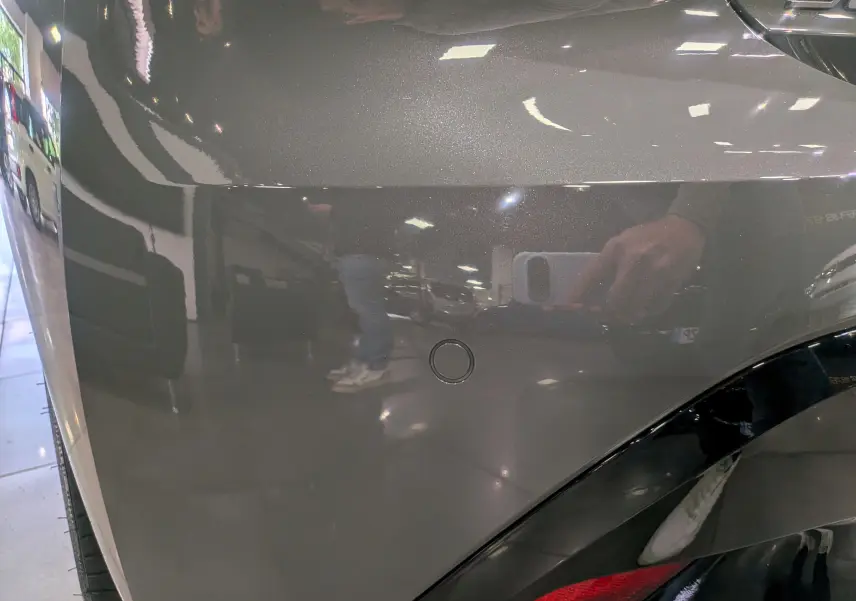 Gros plan sur l'aile arrière droite gris Sélénium d'une Peugeot 308 2026 avec capteur de stationnement visible.