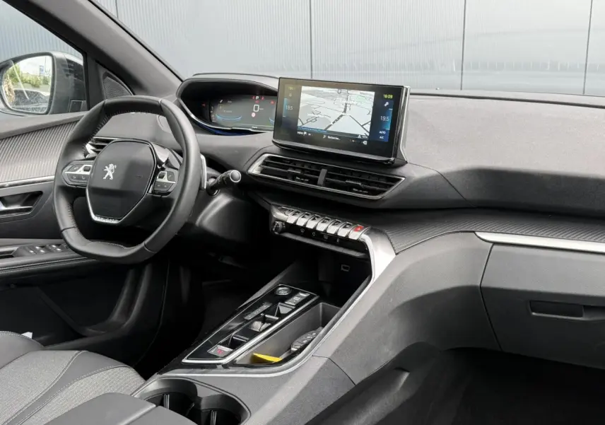 Vue intérieure côté conducteur du Peugeot 3008 Plug-in Hybrid 2024, tableau de bord noir avec écran tactile central et volant compact.
