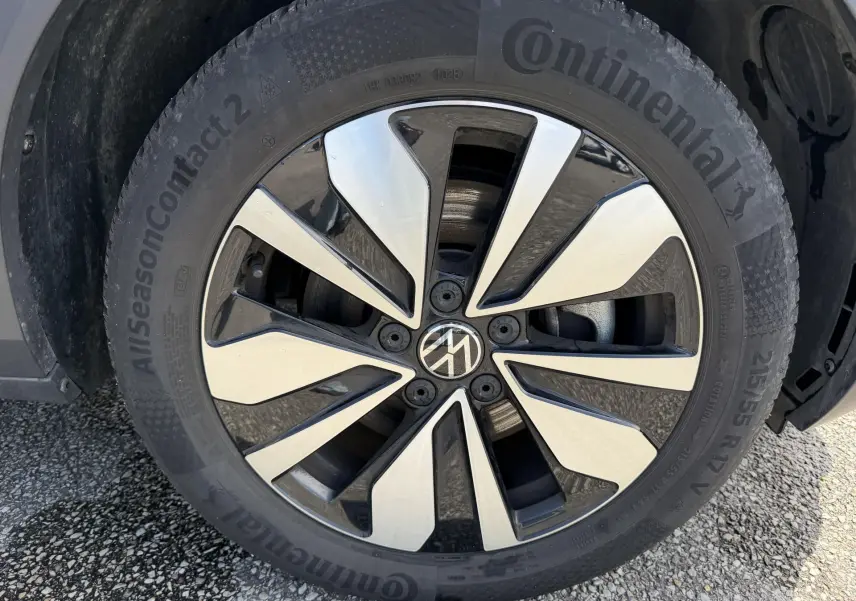 Gros plan sur la roue avant gauche du Volkswagen T-Roc gris, mettant en valeur la jante alliage bicolore et le pneu Continental.