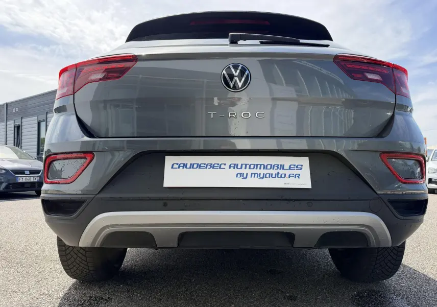 Vue arrière centrée d'un Volkswagen T-Roc gris 2025 avec feux rouges et barres de toit noires visibles.