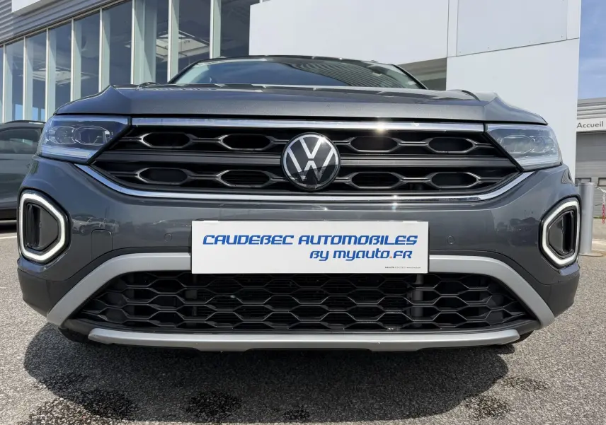 Vue frontale rapprochée du Volkswagen T-Roc gris 2025 avec calandre noire et éclairage LED distinctif.