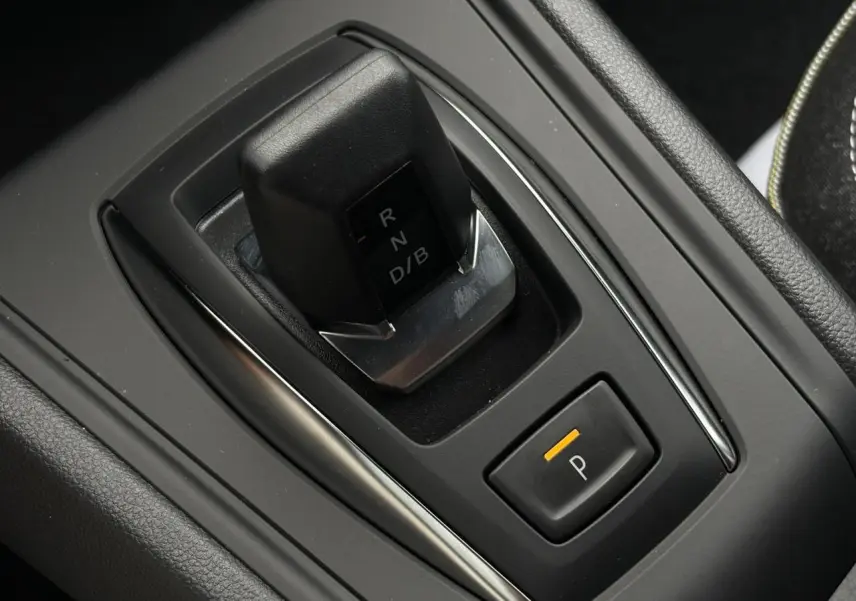 Gros plan sur la commande de boîte automatique noire et bouton de frein de parking du Renault Captur blanc nacré.