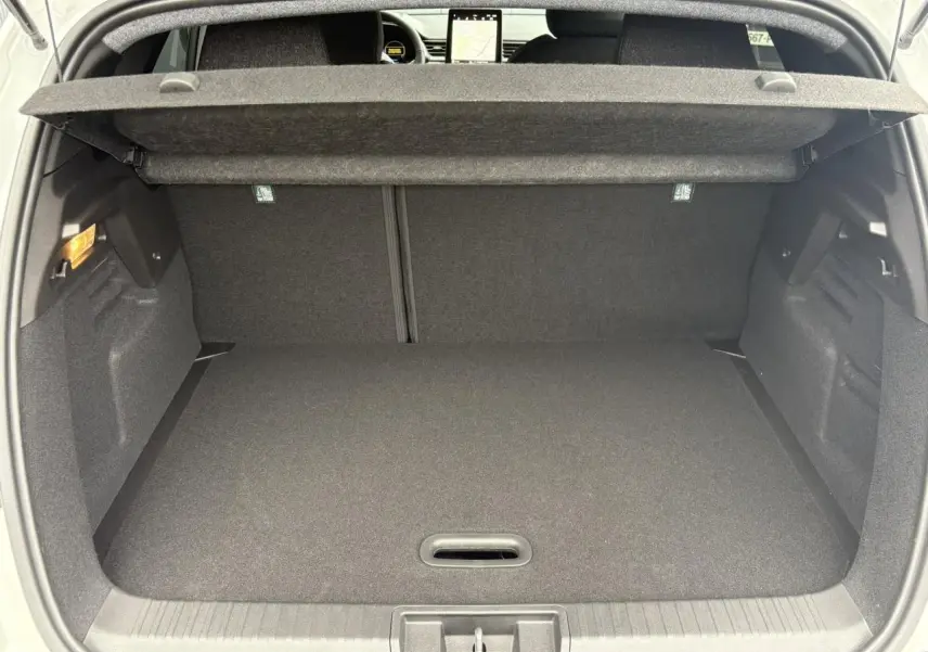 Coffre ouvert vu de l'arrière d'un Renault Captur blanc nacré, espace de chargement vide avec cache-bagages déployé.