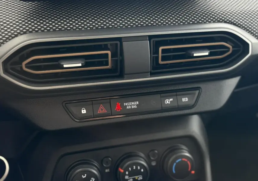 Détail du tableau de bord du Dacia Sandero Stepway 2025, avec aérateurs hexagonaux et commandes de climatisation noires.